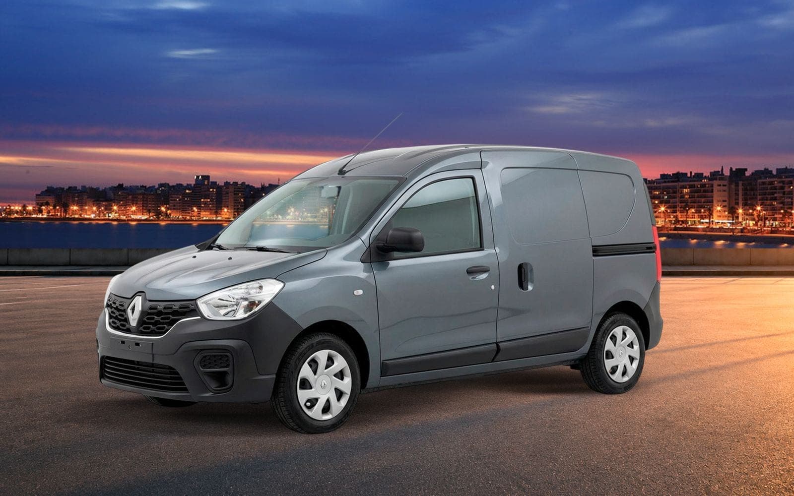 Furgoneta Renault Kangoo Express gris de frente y tres cuartos, con la costa de Montevideo iluminada al anochecer detrás